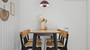 Una mesa de comedor con cuatro sillas, un florero con flores y una lámpara colgante.