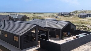 Een modern huis met een schuin dak, grote ramen en een terras.