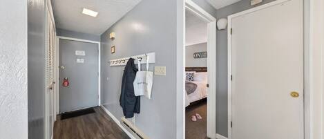 A hallway with a coat rack, a fire extinguisher, and a sign on the wall.