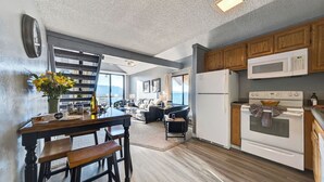 A modern kitchen with a dining area, wooden cabinets, a refrigerator, and a stove. - Beach Front Perch by Avantstay Lakefront Condo + Views + Near Dining and Skiing (South Lake Tahoe)