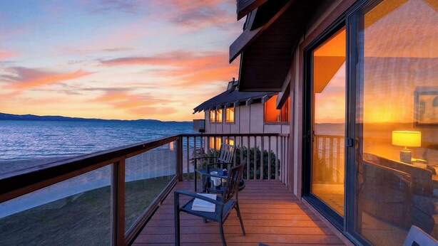 A balcony with a view of the sea at sunset. - Beach Front Perch by Avantstay Lakefront Condo + Views + Near Dining and Skiing (South Lake Tahoe)