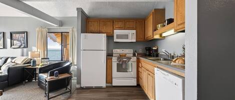 Una cocina compacta equipada con refrigerador, microondas, estufa y lavavajillas.