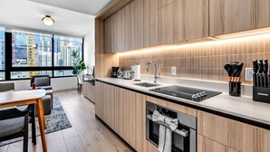 Een moderne keuken met houten kastjes, een zwart aanrecht, een ingebouwde oven en een raam met uitzicht op de stad.