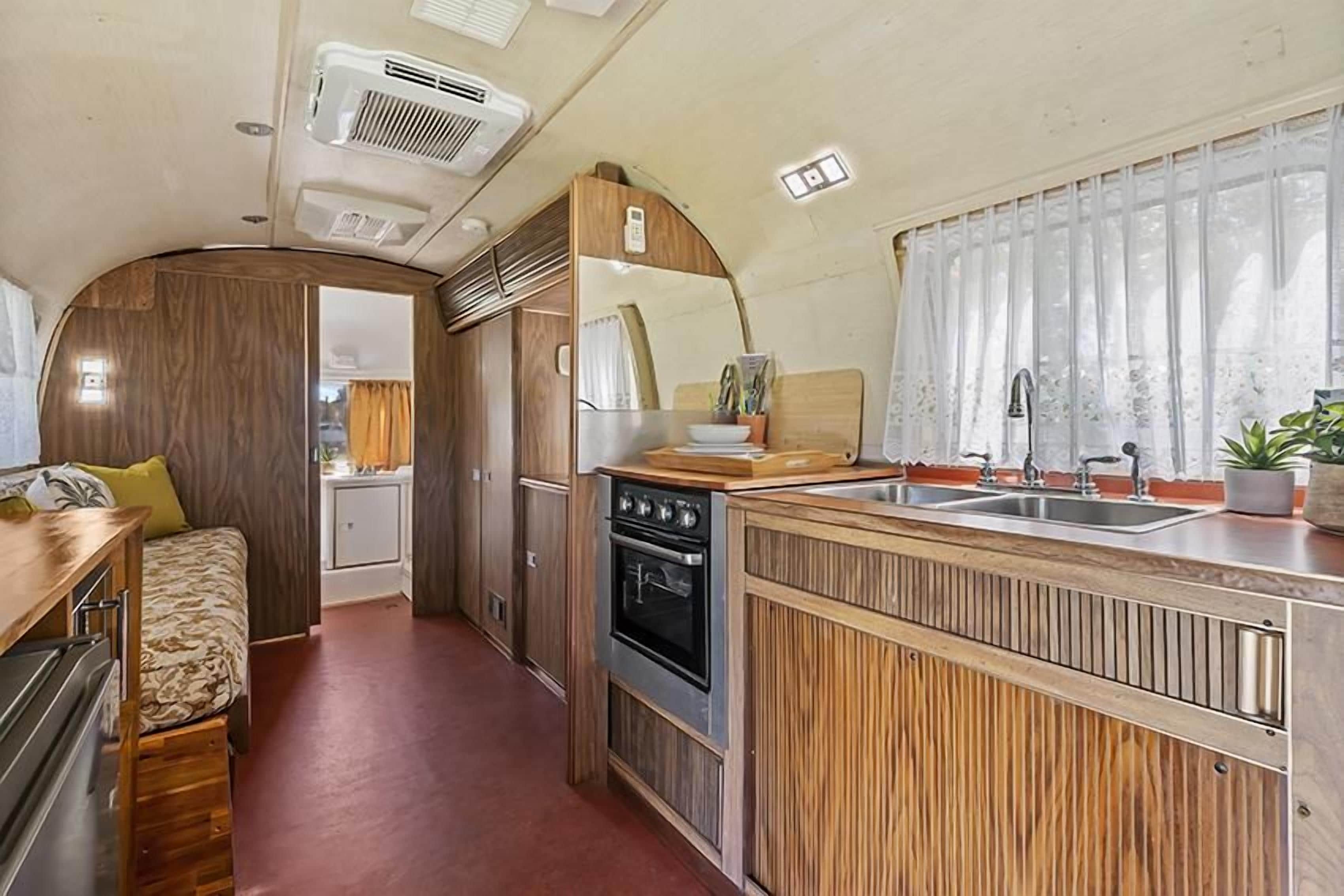 En kompakt autocamper indretning med et tekøkken, spiseplads og en lille opholdsstue.