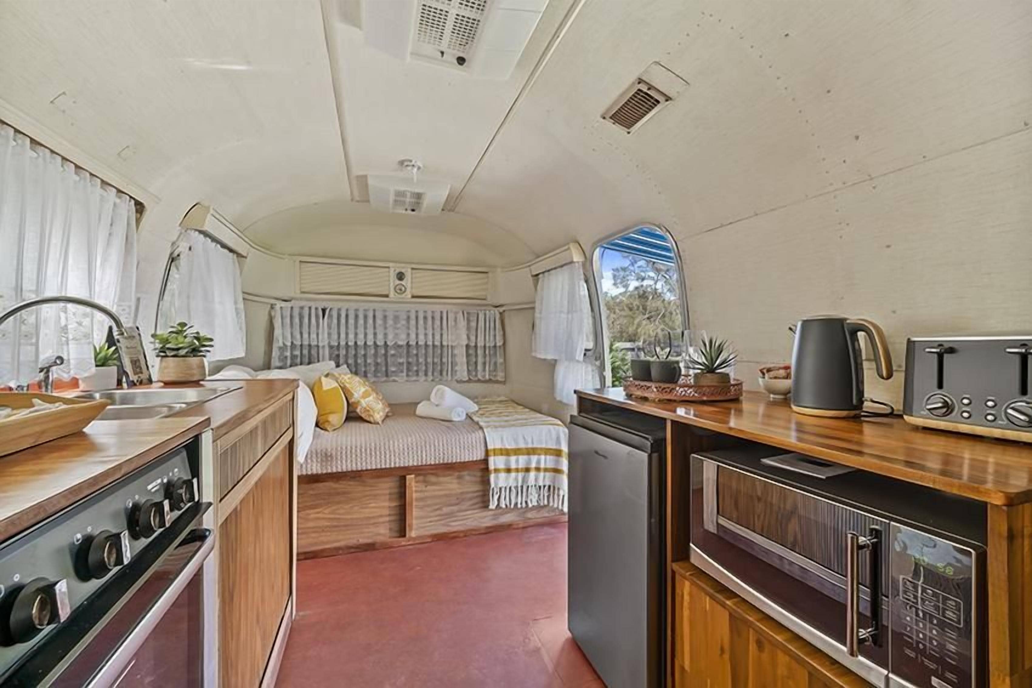 A compact RV kitchen with a stove, sink, and a small refrigerator.