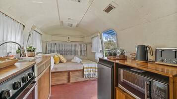 A compact RV kitchen with a stove, sink, and a small refrigerator.