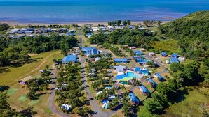 Vista aérea de un resort costero con varias construcciones, una piscina y una playa.