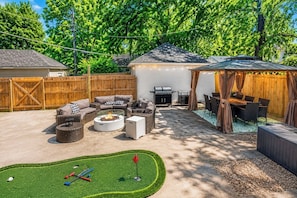 A backyard with a fire pit, outdoor furniture, a grill, and a covered dining area. - Theater Room • Fire Pit + Grill • Sleeps 16 (Kansas City)