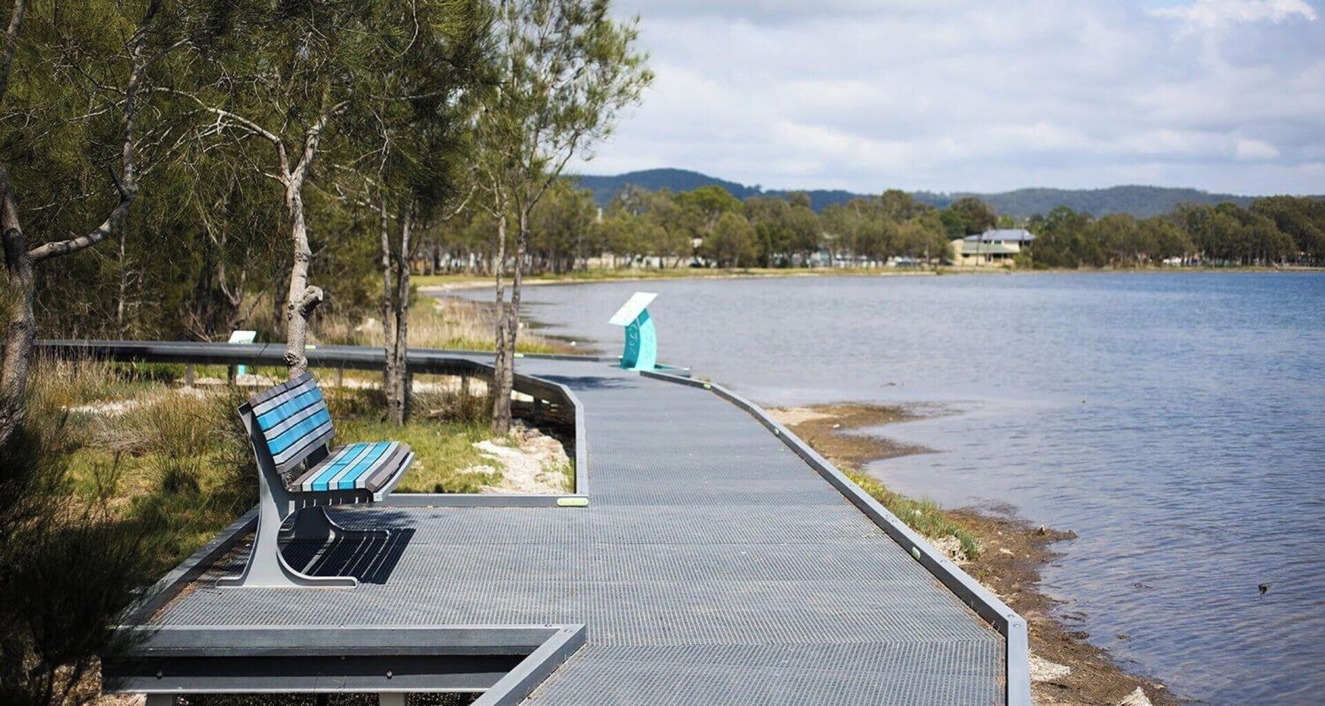 A waterfront walkway with a bench and a viewing platform.