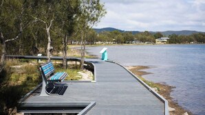A waterfront walkway with a bench and a viewing platform. - KozyGuru | Wyong | Cottage Close to Everything (Wyong)