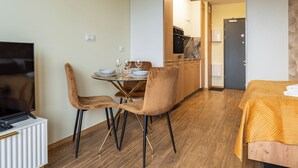 Une chambre d’hôtel équipée d’une télévision, d’une table à manger avec des chaises, d’un coin cuisine et d’un lit.