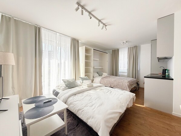 A modern hotel room with two beds, a desk, a wardrobe, and a kitchenette. - Mieszczańska Charming Studio (Wrocław)