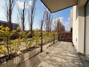 A paved outdoor area with a metal fence, trees, and a building in the background. - Mieszczańska Charming Studio (Wrocław)
