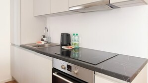 Una cuina moderna amb taulell negre, electrodomèstics d'acer inoxidable i armaris blancs.