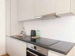 A modern kitchen with a black countertop, stainless steel appliances, and white cabinetry. - Mieszczańska Charming Studio (Wrocław)