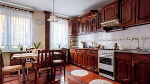 Een keuken met houten kastjes, een fornuis en een eethoek met stoelen en een tafel.
