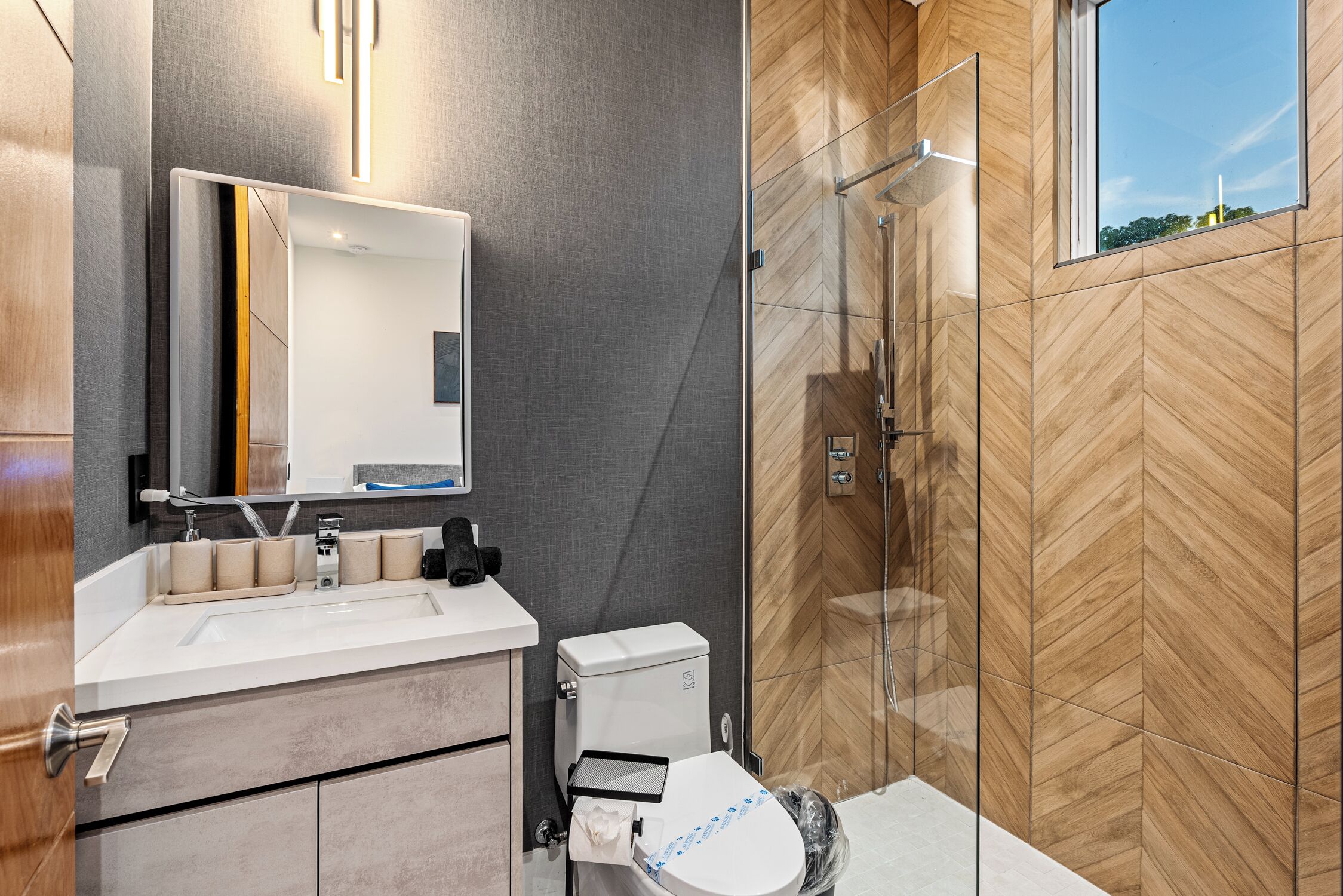 Een moderne badkamer met een grote spiegel, toilet en douche.