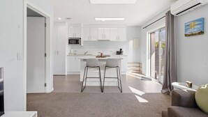 Une cuisine moderne avec des meubles blancs, un four à micro-ondes et un coin repas équipé de deux chaises.