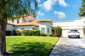 A residential house with a well-maintained lawn, a garage, and a driveway.