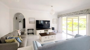 Ein modernes Wohnzimmer mit einer Couch, einem Couchtisch, einem Fernseher und einem großen Fenster.