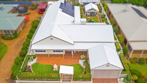 Ein Hausmodell mit geneigtem Dach, Solaranlage, Garage und einem gepflegten Garten.