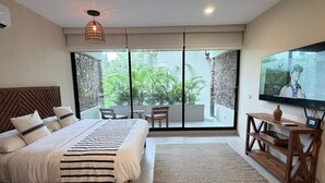 Quarto moderno com cama grande, televisão e porta de vidro deslizante para uma varanda.