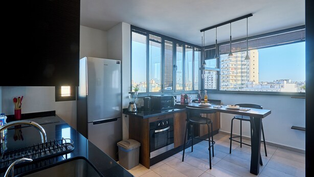 A modern kitchen with a large window, stainless steel appliances, and a dining area with bar stools. - Spot Bonheur downtown Wi-Fi Fiber + balcony (Casablanca)