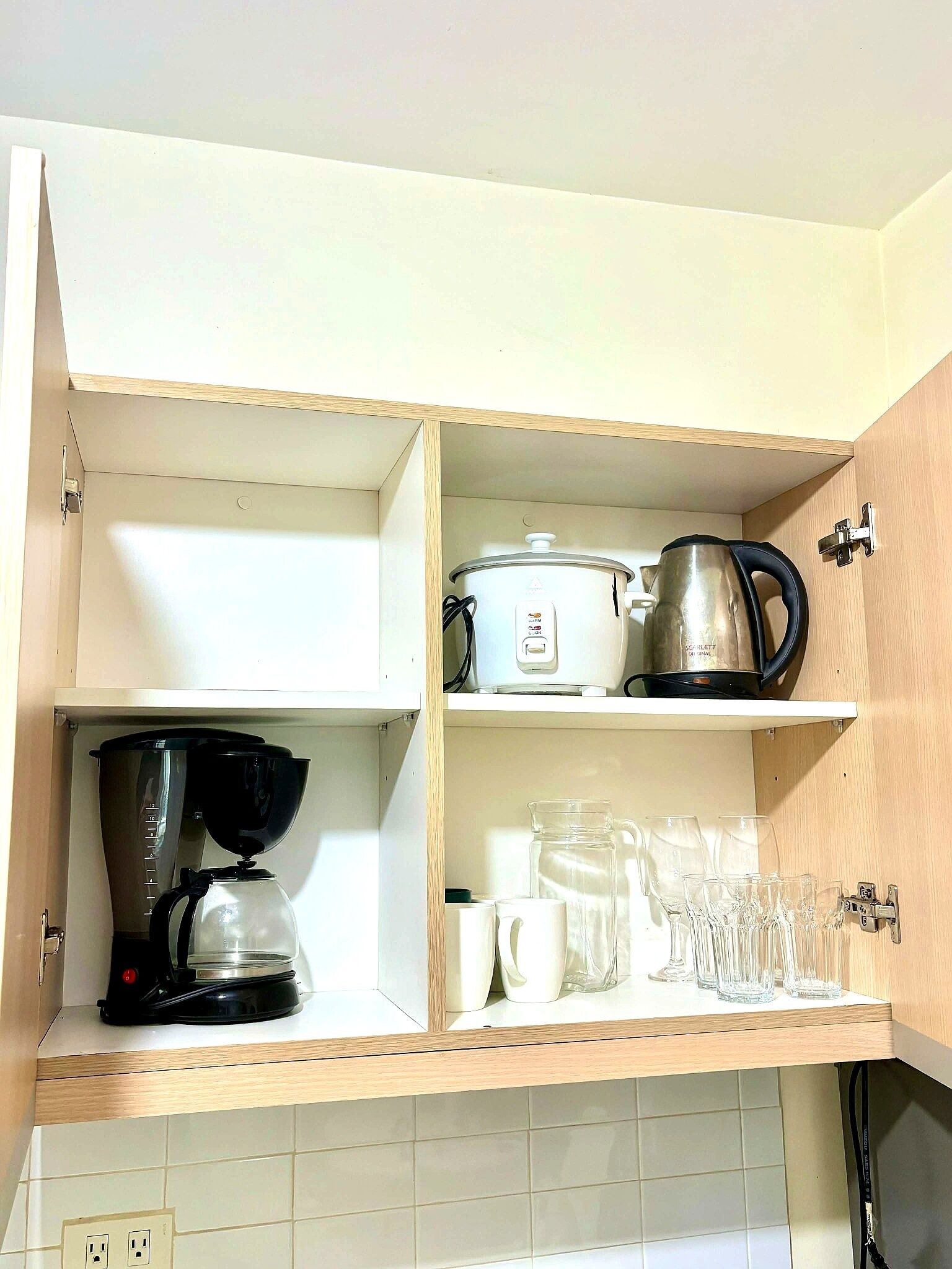 Una cocina con una cafetera, una olla de cocción lenta y un hervidor sobre la encimera.