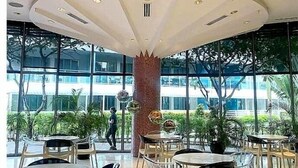 A modern interior with a central column, round tables, and chairs, and large windows offering a view of the outside. - Resort-Style Pool View Staycation Near NAIA Airport | Affordable & Relaxing (Parañaque)