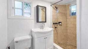 A bathroom with a toilet, sink, mirror, and shower. - Lovely 1-bedroom studio with AC in vibrant Los Angeles (Los Angeles)