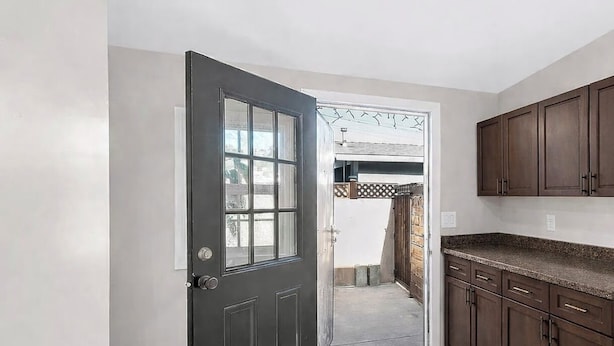 A kitchen with dark wooden cabinets, a tiled floor, and a door leading to an outdoor area. - Lovely 1-bedroom studio with AC in vibrant Los Angeles (Los Angeles)