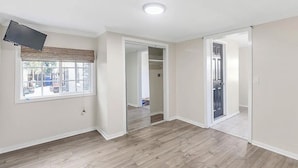 A room with a large window, a flat-screen TV mounted on the wall, and a sliding glass door leading to another room. - Lovely 1-bedroom studio with AC in vibrant Los Angeles (Los Angeles)