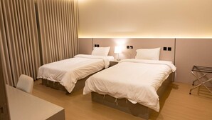 Une chambre d’hôtel avec deux lits, un bureau et une chaise.