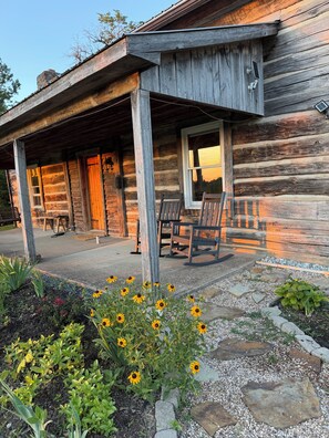 A rustic log cabin with a porch, outdoor seating, and a garden with sunflowers. - Historic Antique Cabin Red River Gorge on 200 acres.  (Frenchburg)