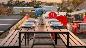 Mesa de jantar posta ao ar livre com cadeiras, um vaso com flores e vista para a paisagem.