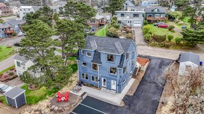 Un immeuble résidentiel de deux étages avec un jardin devant, un petit abri de jardin et une allée.