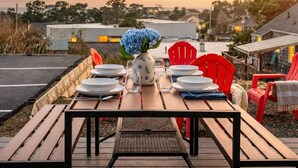 A dining table set outdoors with chairs, a vase with flowers, and a view of the landscape.