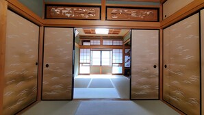 Perinteinen japanilainen huone, jossa on tatamimatto, lintukuviollinen liukuovi ja näkymä shoji-paperi-ikkunan läpi.