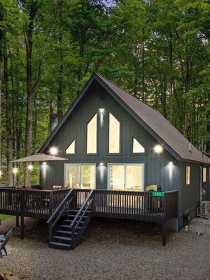 A cabin with a deck, a staircase, and a large window. - Casa Camilo: Highly Rated Pocono Chalet with Hot Tub in Arrowhead Lake (Pocono Lake)
