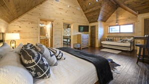 Une chambre située dans un chalet en rondins, avec un lit, un canapé, une télévision et une fenêtre.