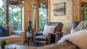 L’intérieur chaleureux d’un chalet avec un canapé en cuir, une table en bois et un tableau accroché au mur.