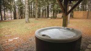 Un jacuzzi en un área boscosa con una estructura de madera sobre él.