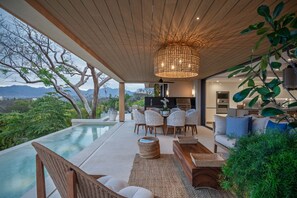 An infinity pool with a wooden ceiling and outdoor furniture, including chairs and a sofa, with a view of mountains. - Villa Monarca in Punta Mita (Punta de Mita)
