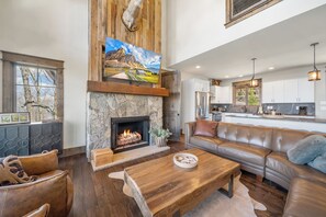 Amplia sala de estar con chimenea, sofá de cuero y una mesa de comedor.