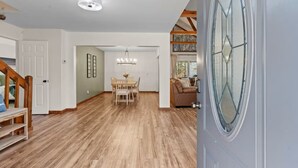 A spacious interior with a wooden floor, a dining area with a chandelier, and a large window with a decorative glass design. - Owl & Ember - Walk to Coosawatee Resort Center! Grill, 2 Kings, 3 Smart TV's (Ellijay)