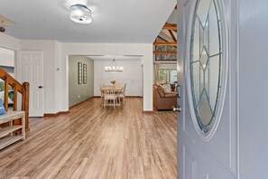 A spacious interior with a wooden floor, a dining area with a chandelier, and a large window with a decorative glass design. - Owl & Ember - Walk to Coosawatee Resort Center! Grill, 2 Kings, 3 Smart TV's (Ellijay)