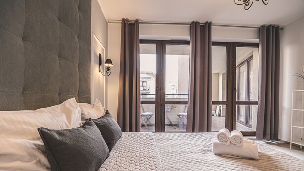 Ein Hotelzimmer mit einem großen Bett, einem Blick auf den Balkon und einem ordentlich bezogenen Bett mit Handtüchern.