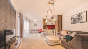 Ein modernes Wohnzimmer mit einer Couch, einem Couchtisch und einem Fernseher auf einem Holzboden.