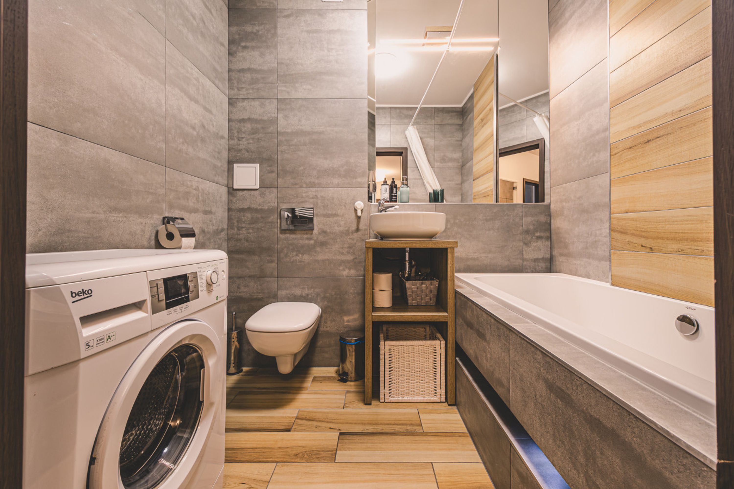 A modern bathroom with a washing machine, toilet, sink, and bathtub.