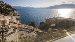 Une vue sur la côte, avec un ciel dégagé, une étendue d’eau et un bâtiment doté d’un escalier menant à une terrasse.